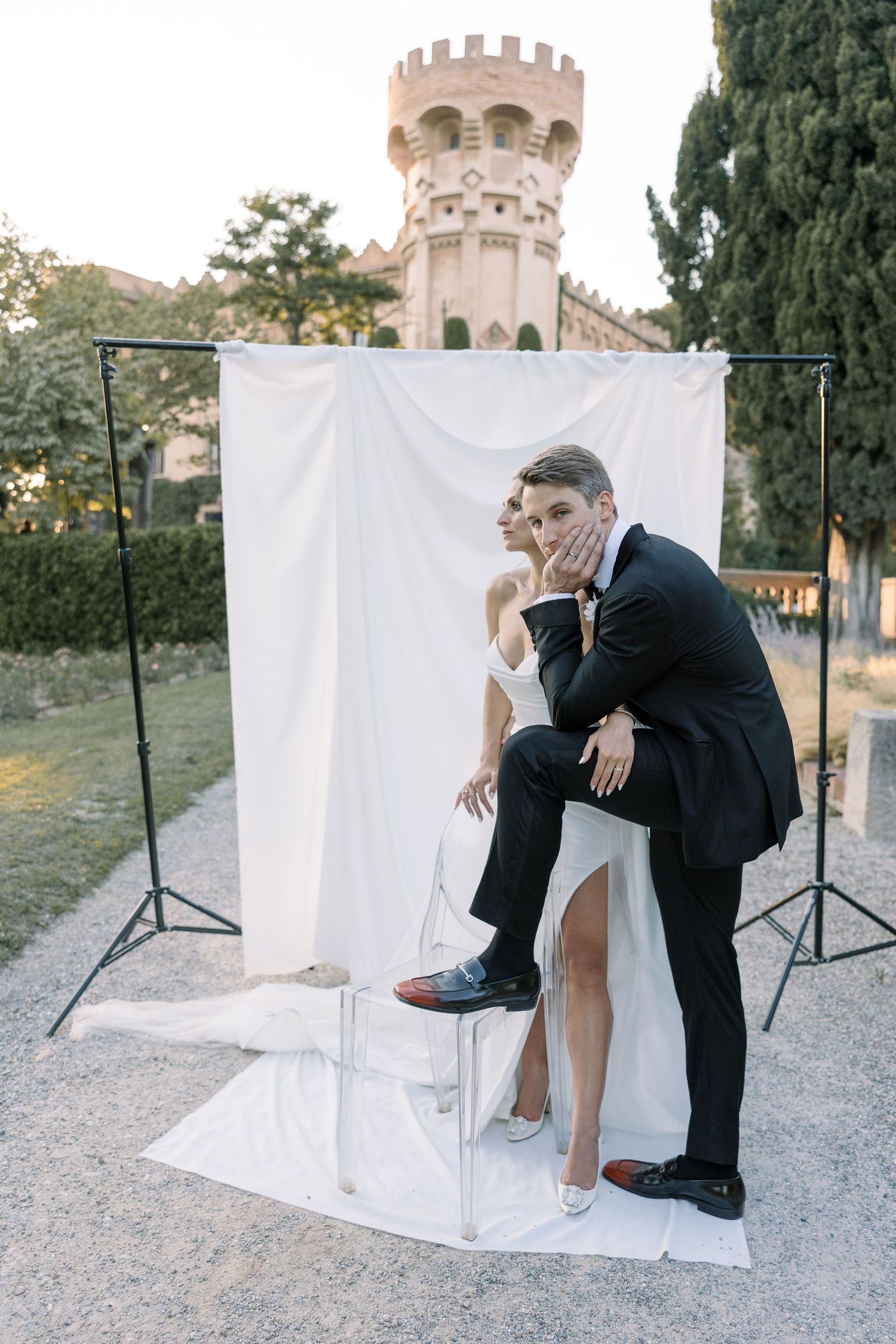 Creative wedding portrait with couple posing on white blocks in front of castle tower.