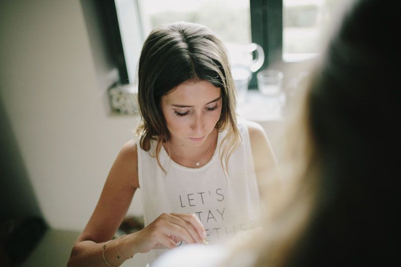 Person wearing a white tank top with 'Let's Stay' text looking down during prep.