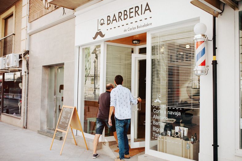 Exterior view of a modern barbershop storefront with traditional barber pole.