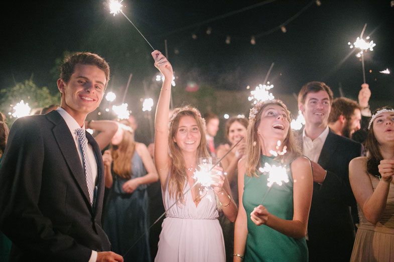 Wedding guests celebrate with sparklers during an outdoor evening celebration.