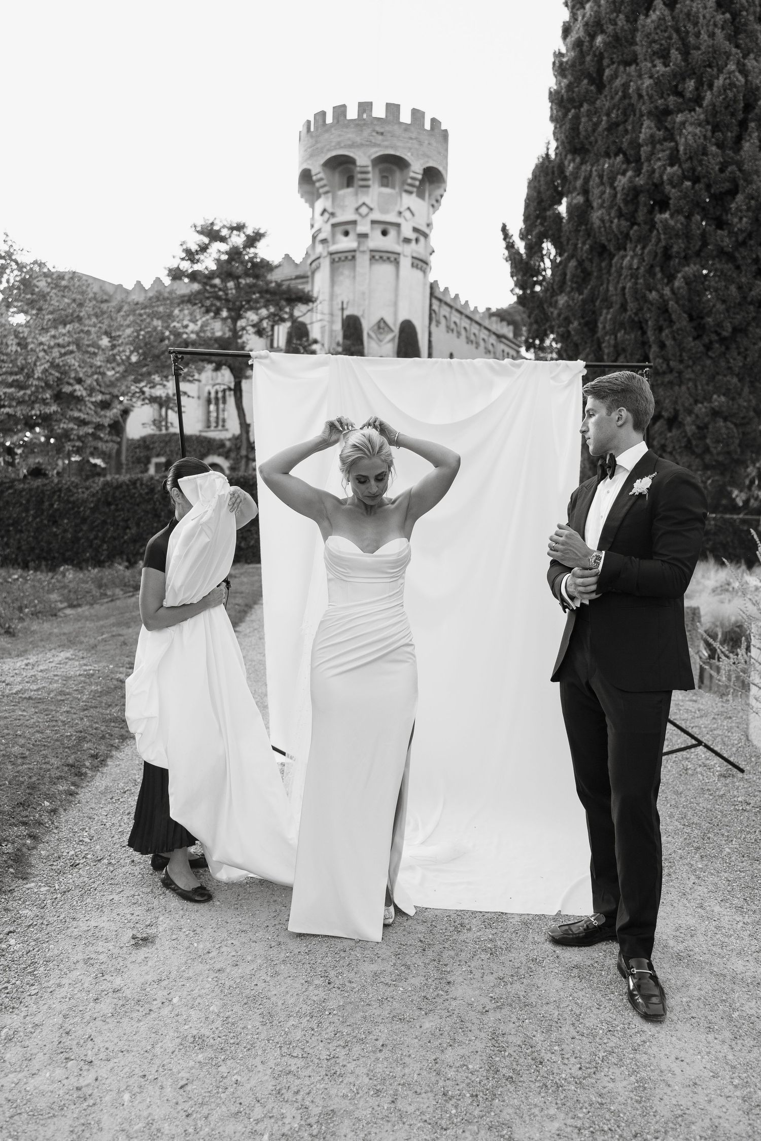 Candid behind-the-scenes wedding photoshoot moment with castle tower in background.