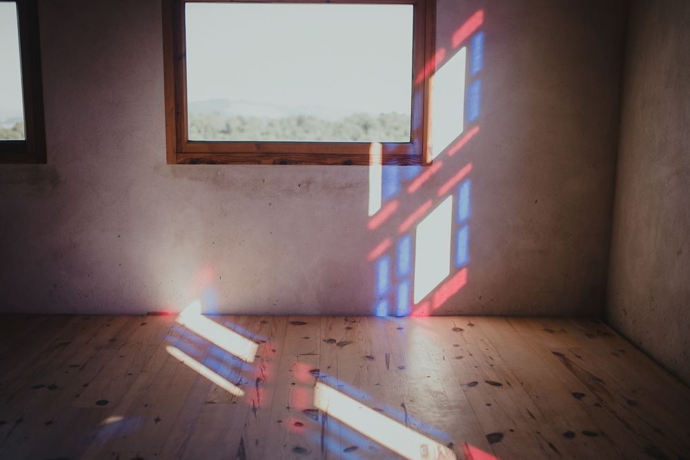 Colorful light prisms reflect on empty room walls creating geometric rainbow patterns.
