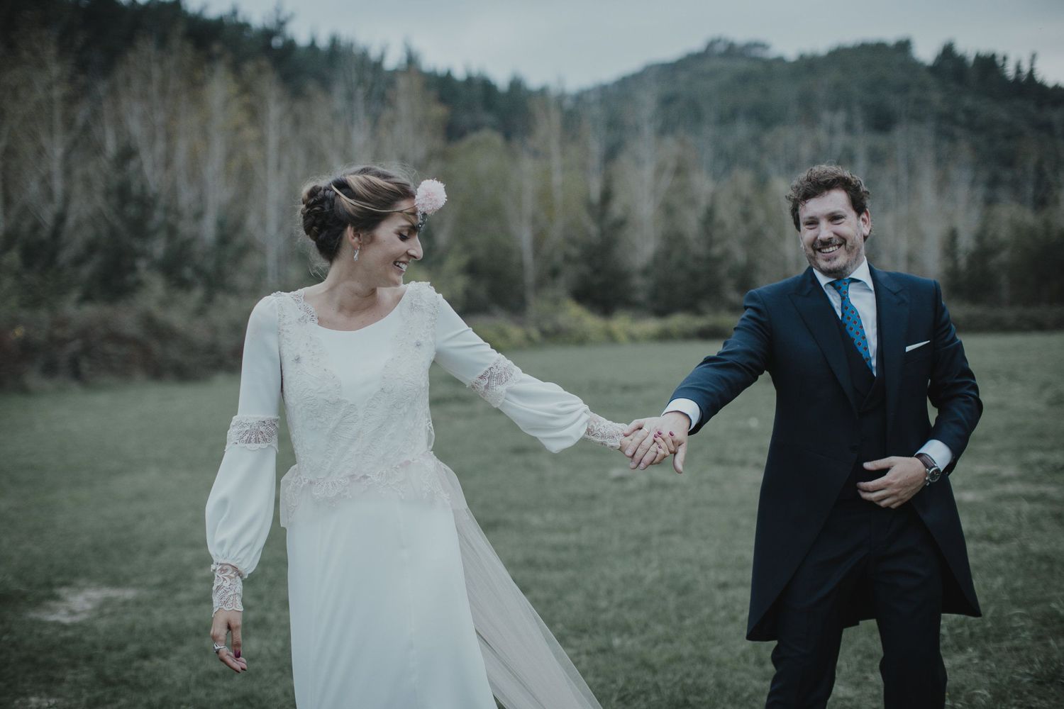 A couple shares a playful moment in wedding attire against a mountain backdrop.