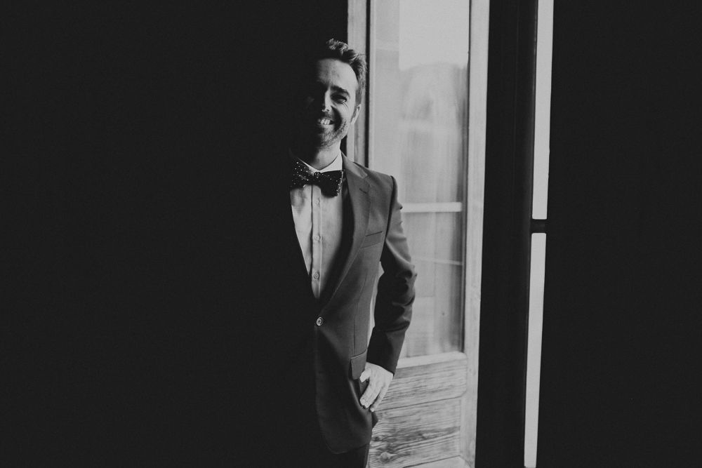 Classic black and white portrait of a suited figure in formal attire near a window.