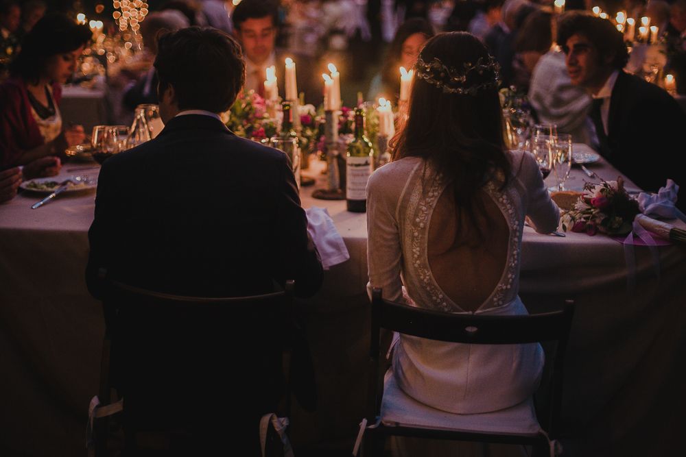 A couple sits at a candlelit reception table creating an intimate atmosphere.