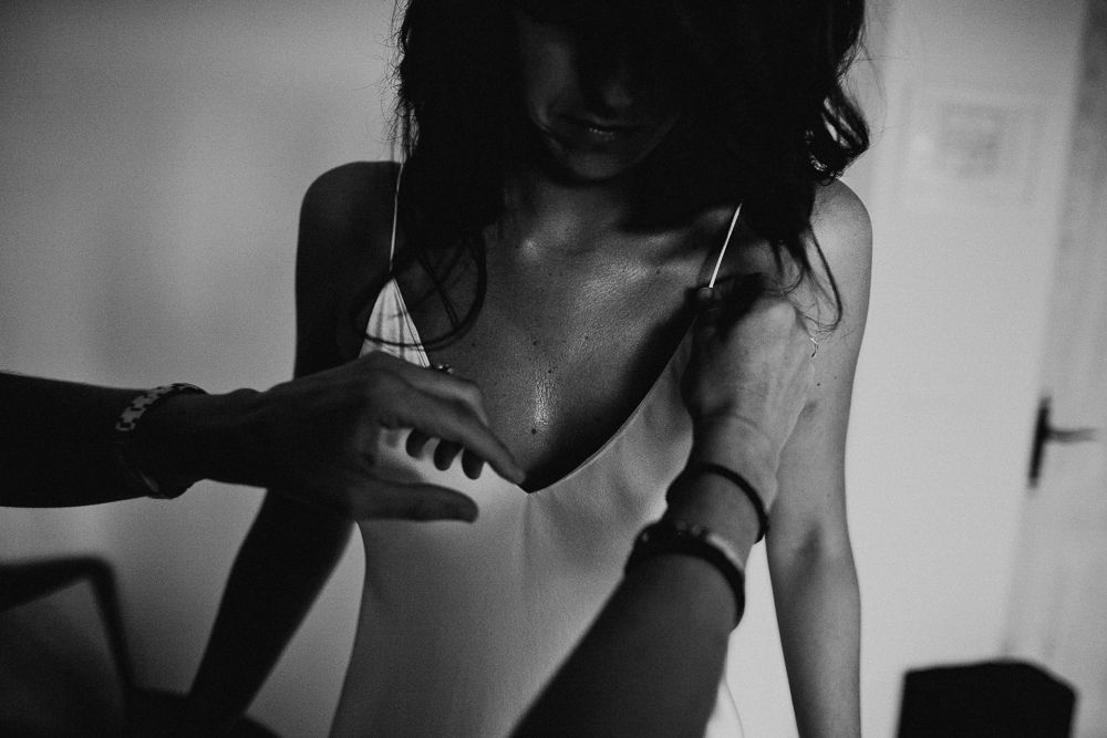 Intimate black and white photograph showing final dress adjustments before a wedding.