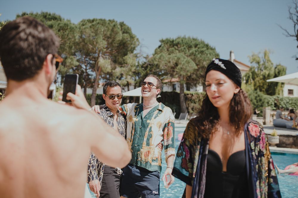 Group of people gathered around outdoor swimming pool on sunny summer day.