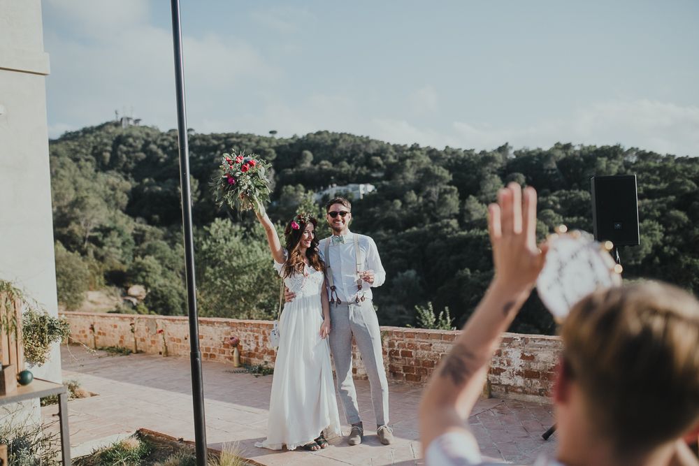 Wedding celebration at an outdoor venue with stone walls and mountain backdrop.
