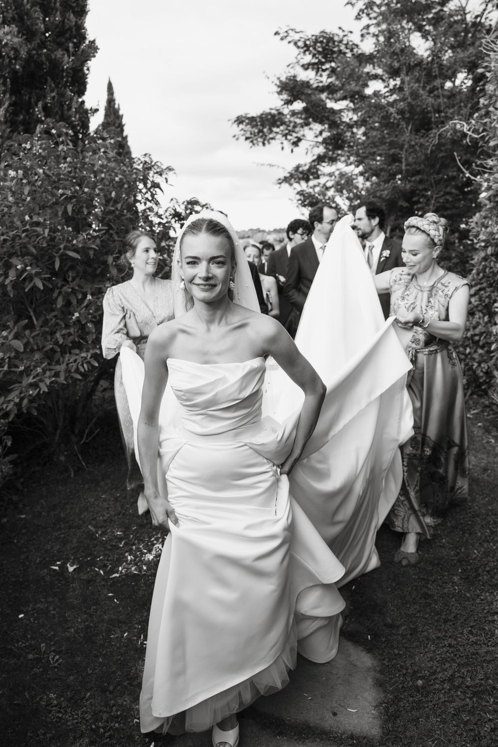 Candid moments of bride in flowing white dress during outdoor wedding celebration.