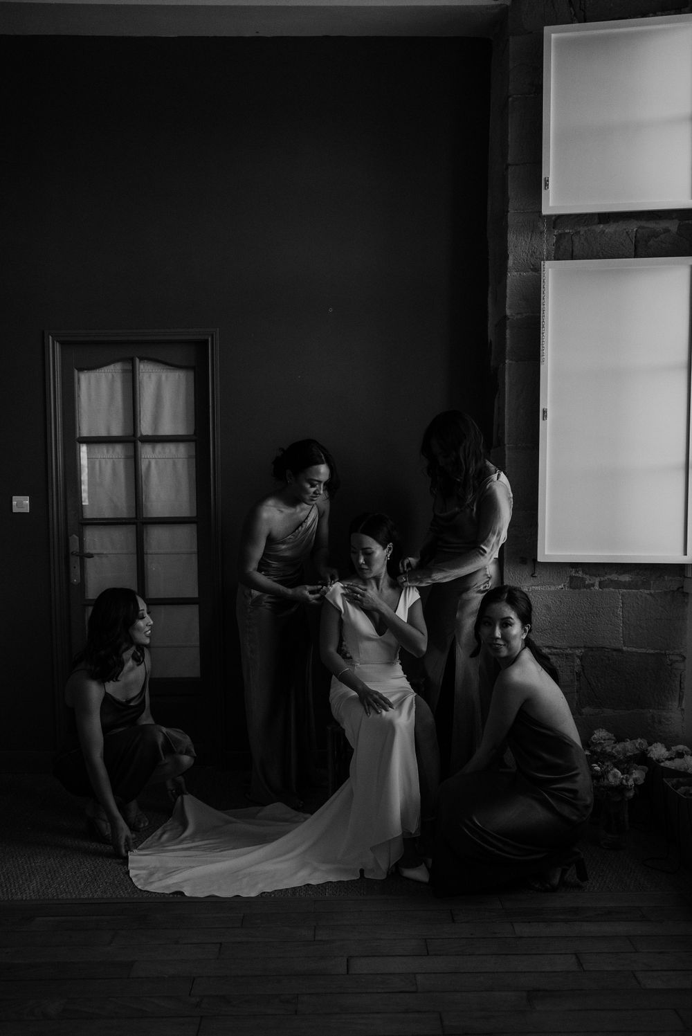 A black and white photo of wedding preparations in a dimly lit room.