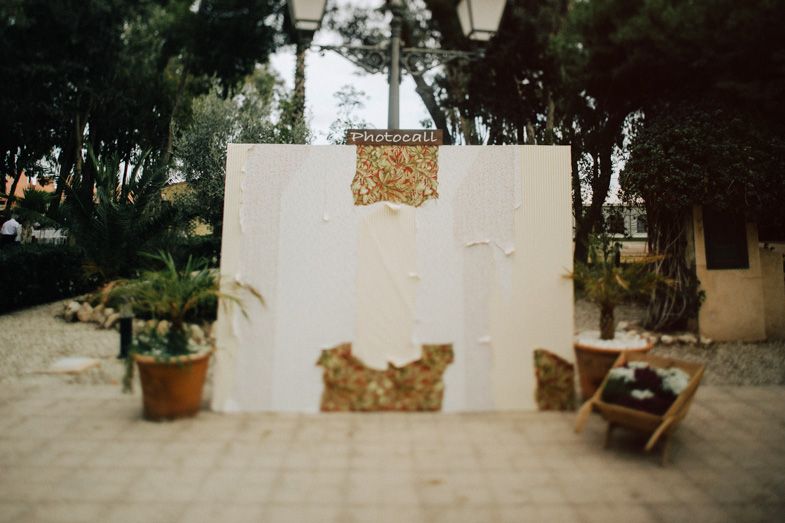 A weathered white wall with peeling texture flanked by potted plants in a Mediterranean setting.