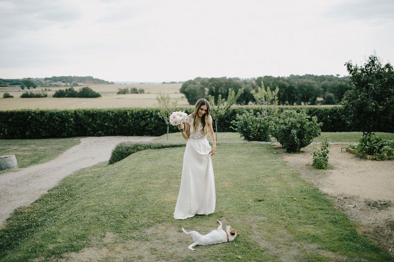 A white wedding dress in a scenic garden landscape with a dog resting nearby.