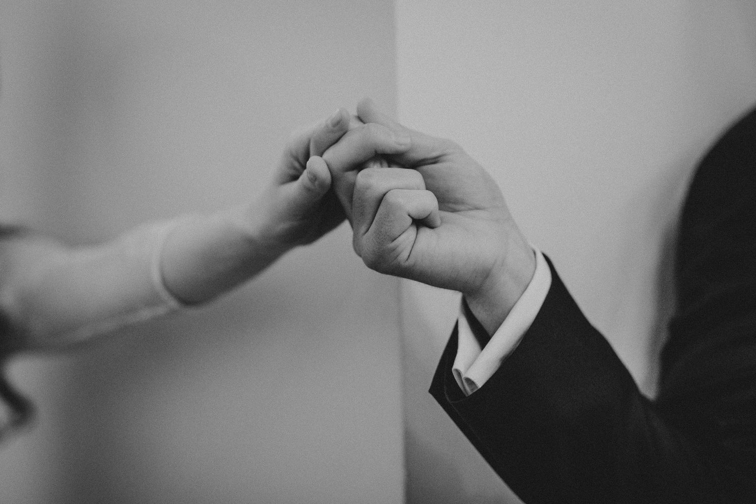 Black and white close-up of two hands joining together in an elegant gesture.