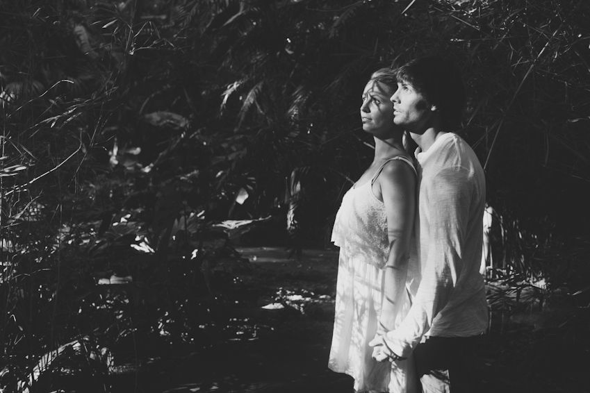 A romantic black and white portrait of a couple standing back-to-back outdoors.