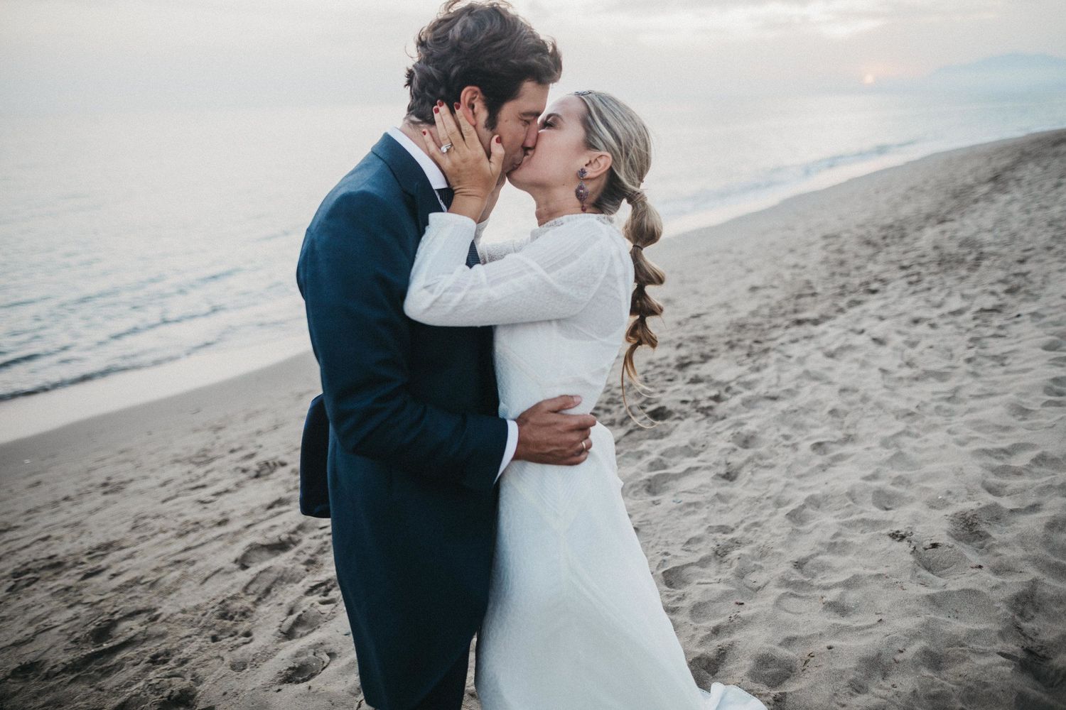 Romantic moment between newlyweds on sandy beach at dusk.
