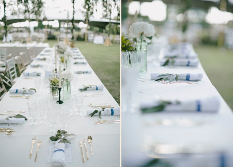 Elegant white wedding reception table settings with floral centerpieces and place cards.