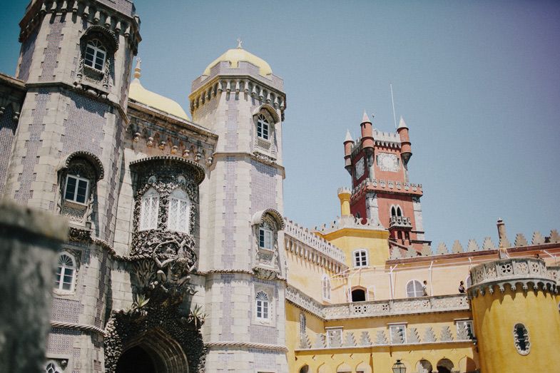 Ornate towers and architecture of the historic Pena Palace in Sintra, Portugal with yellow and white facades.