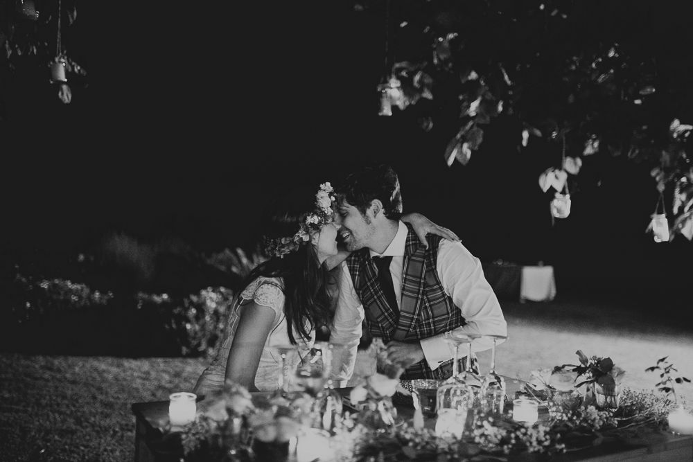 Romantic evening table setting with hanging lights and floral decorations.