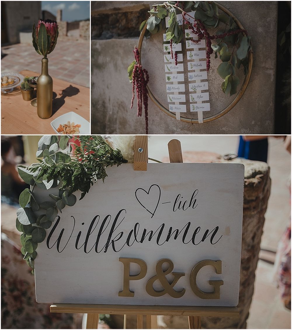 Wedding welcome sign with German text 'Willkommen' and initials P&G decorated with greenery.