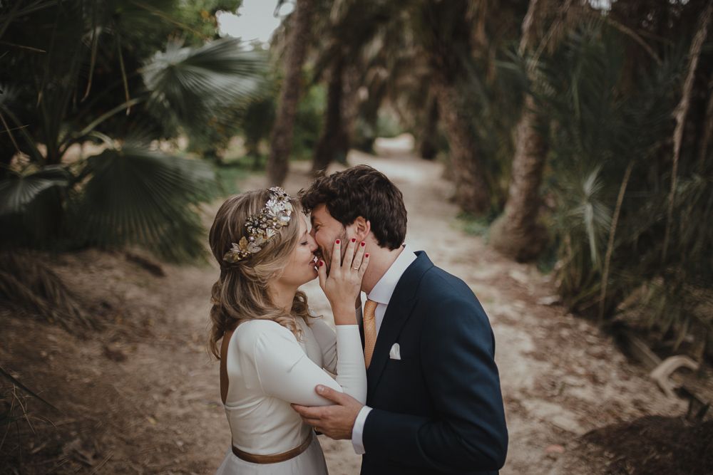An intimate wedding moment captured on a path surrounded by palm trees.