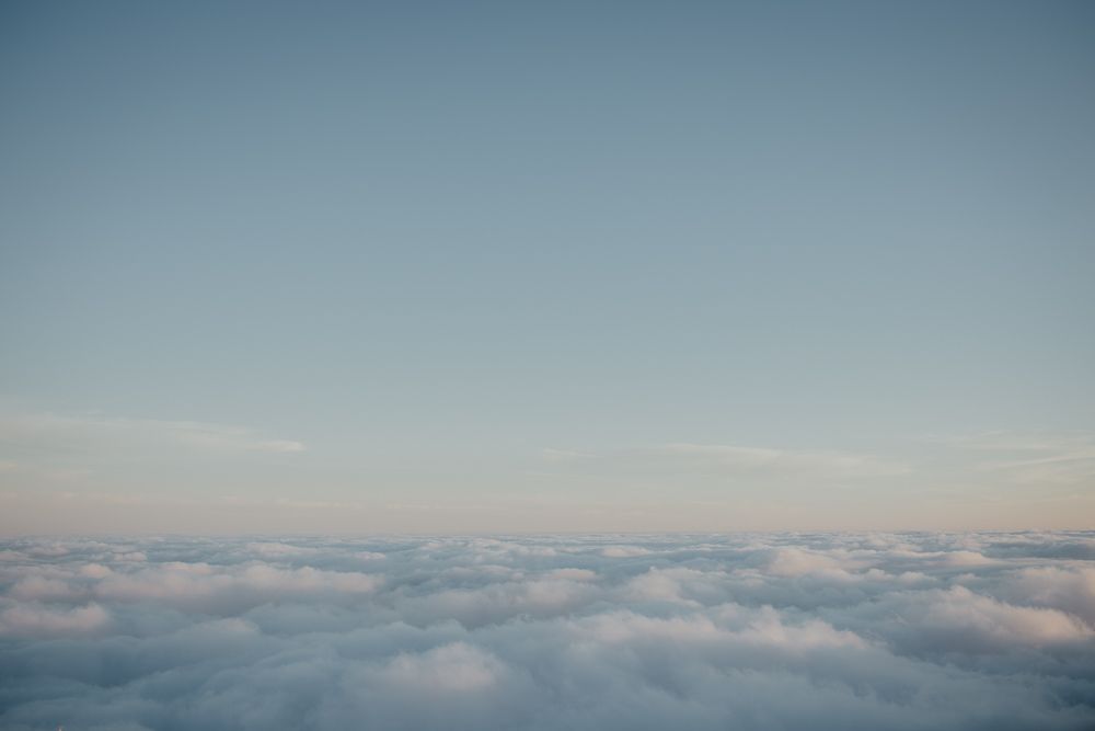 Ethereal view of fluffy white clouds stretching to the horizon under blue sky.