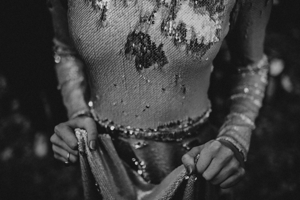 Black and white detail shot showing hands adjusting a sequined vintage dress.