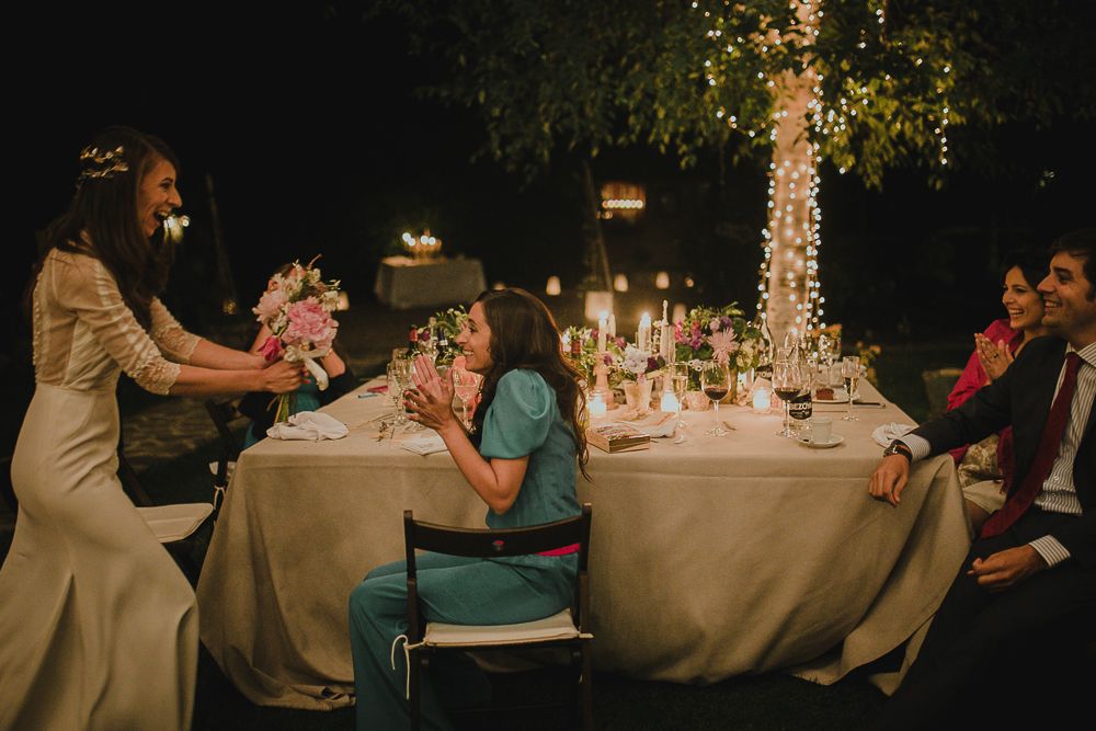 Guests seated at an elegantly decorated outdoor dinner table with string lights overhead.