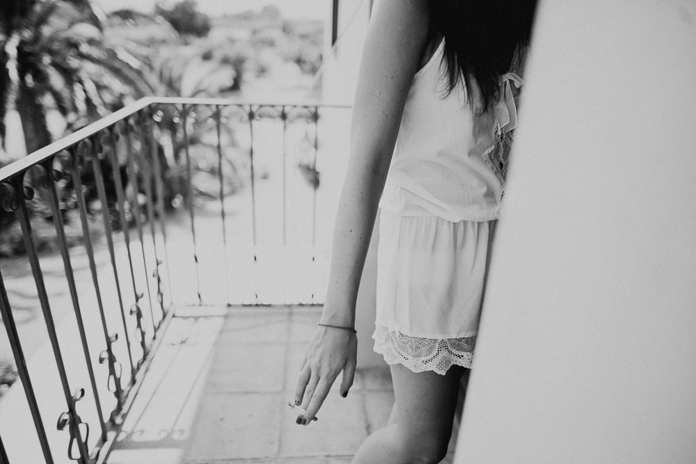 Black and white photo of someone wearing white lace shorts on a balcony.