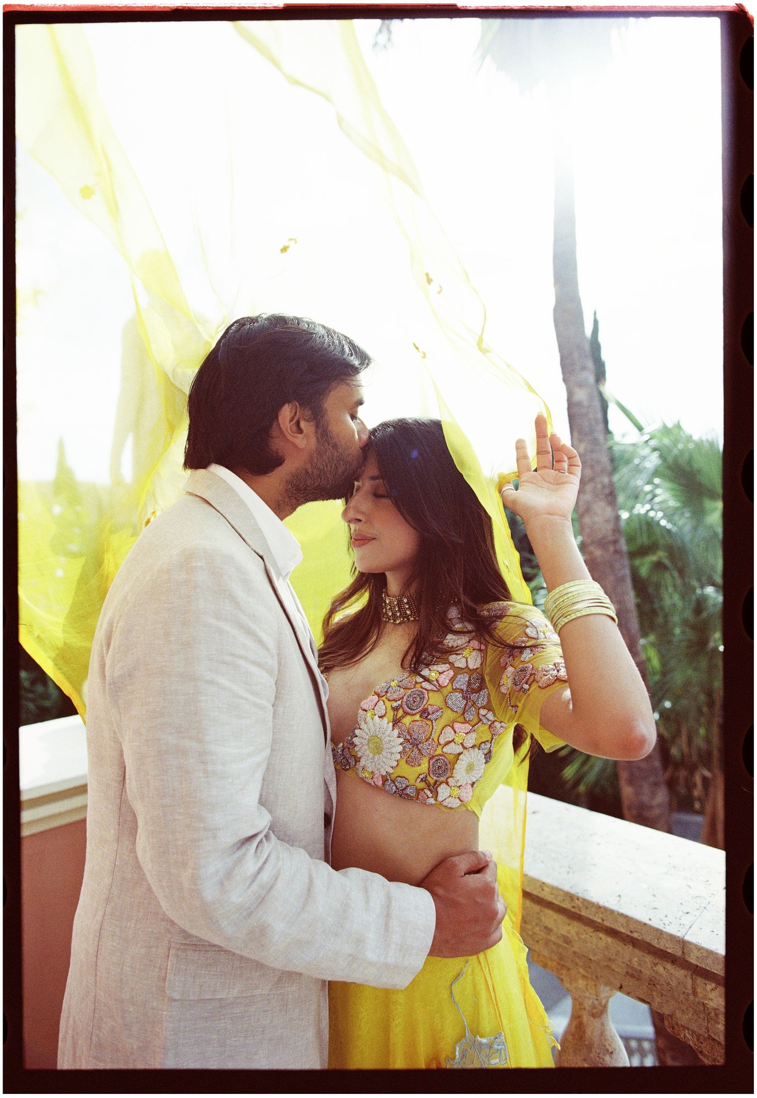 Jag kissing Elina on the forehead beneath yellow fabric, photographed on film.
