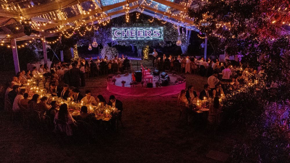 An evening wedding reception setup with circular tables and ambient lighting under string lights.