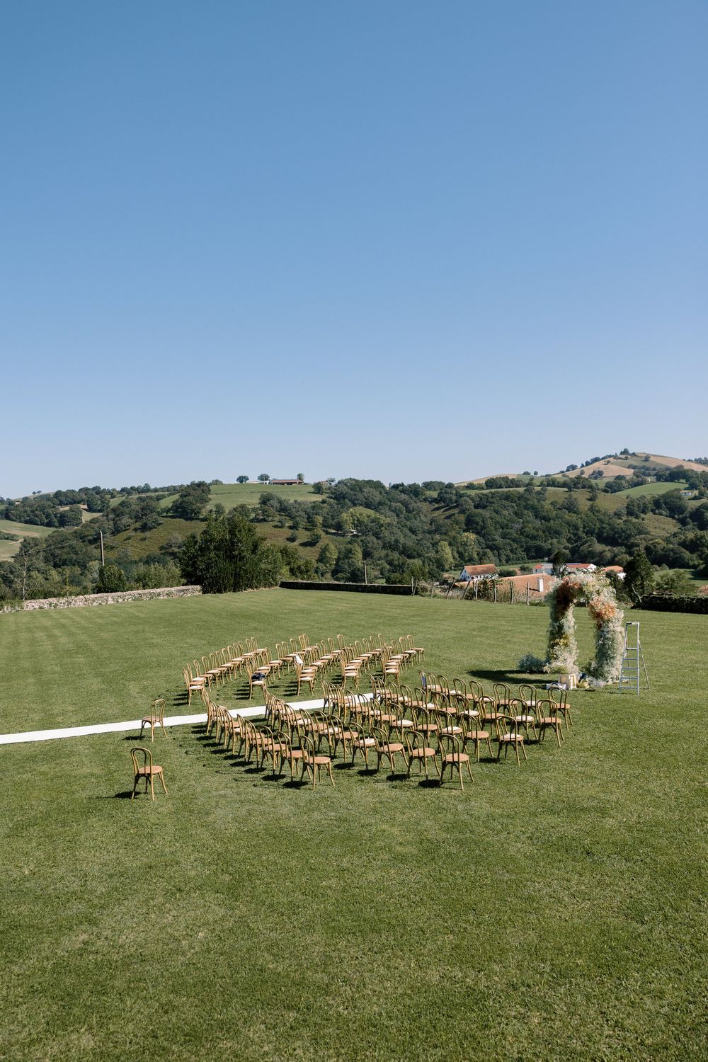 Wooden chairs arranged on a hillside for an outdoor wedding ceremony with mountain views.