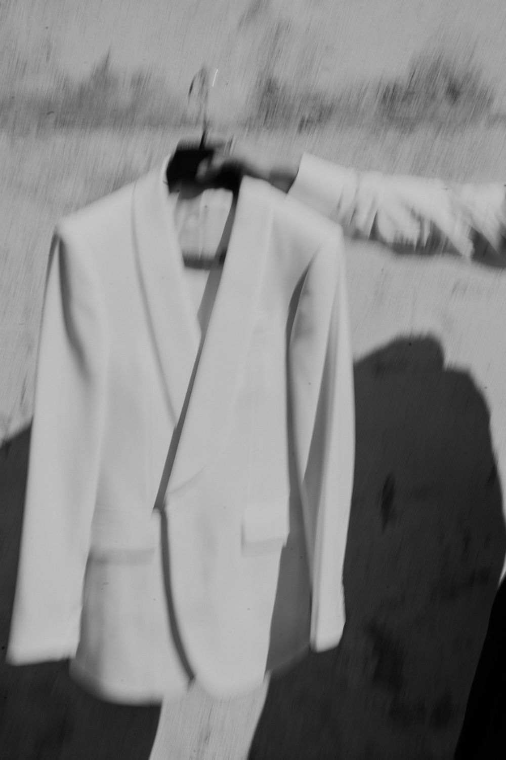 Row of light colored formal suits hanging in preparation for wedding day.