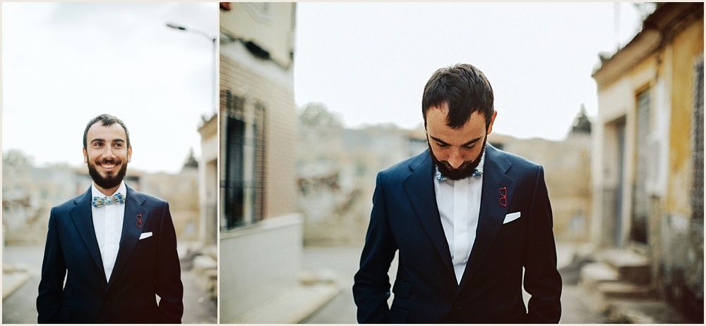 Man in navy suit and bowtie photographed on city street.