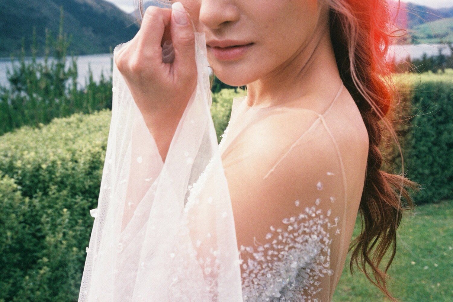 Close-up detail of a wedding dress with delicate pearl beading and sheer fabric.