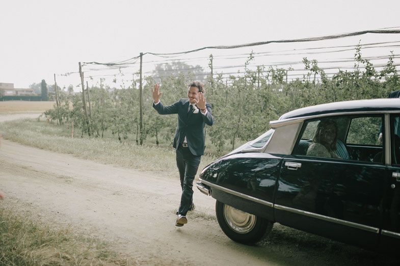 Vintage black car parked on a dirt road near vineyard.