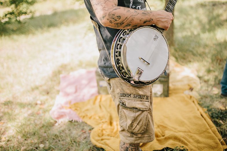 Close-up view of a vintage banjo being played on a yellow blanket outdoors.
