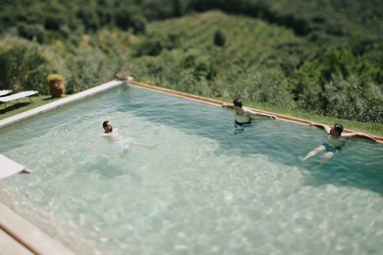 People enjoying a swim in an infinity pool overlooking rolling hills and mountains.