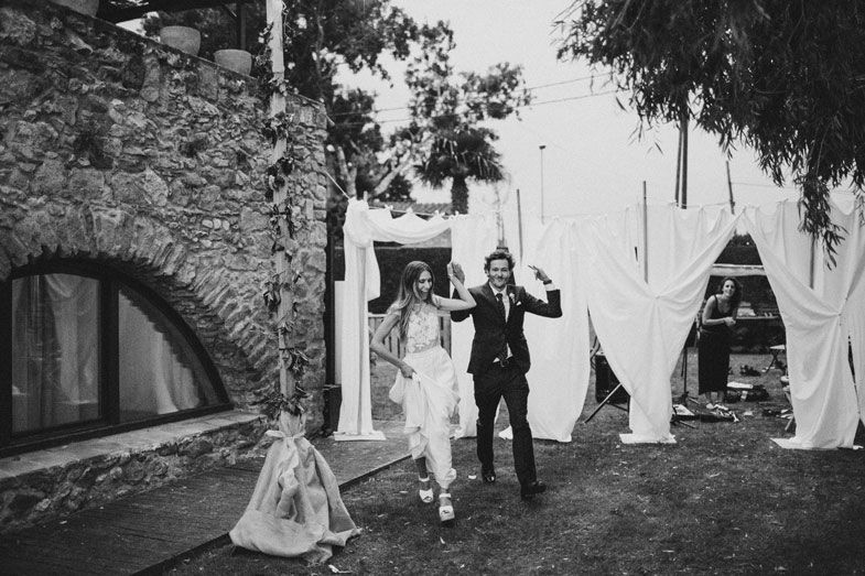 A celebratory moment captured in black and white outside a stone archway with flowing white fabric decor.