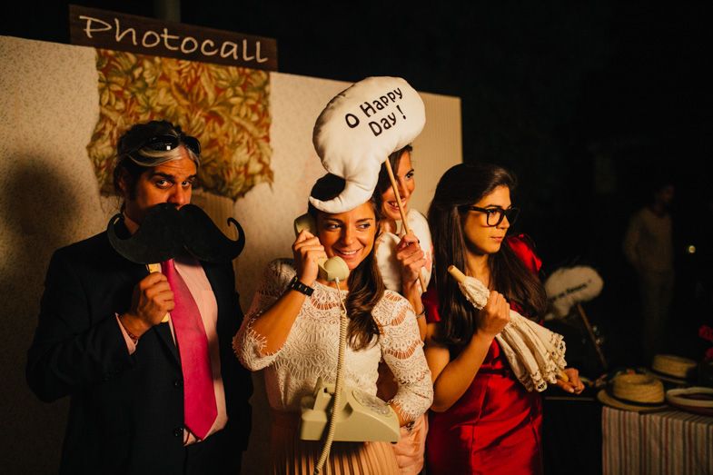 Wedding guests having fun with props at a photo booth during the reception.