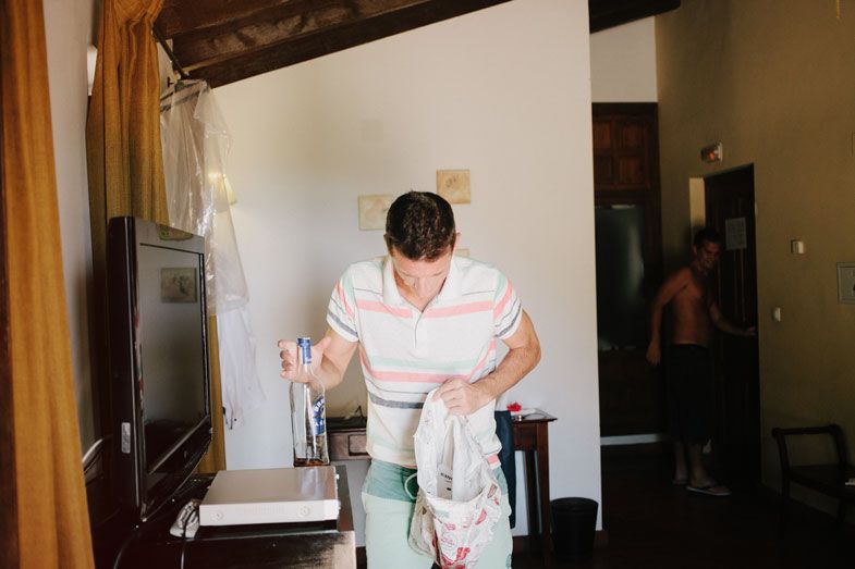 Person in white shirt and mint green pants getting dressed in a simple room.