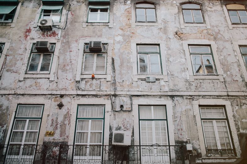Weathered facade of an old Portuguese apartment building with peeling paint and traditional windows.