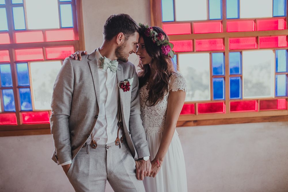 Romantic wedding moment captured against vibrant red and blue window backdrop.