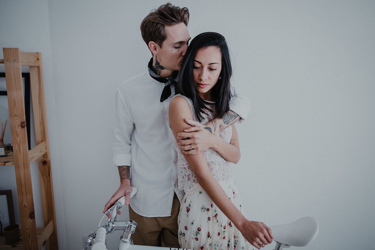 A romantic couple embraces in an intimate indoor photoshoot with minimalist decor.
