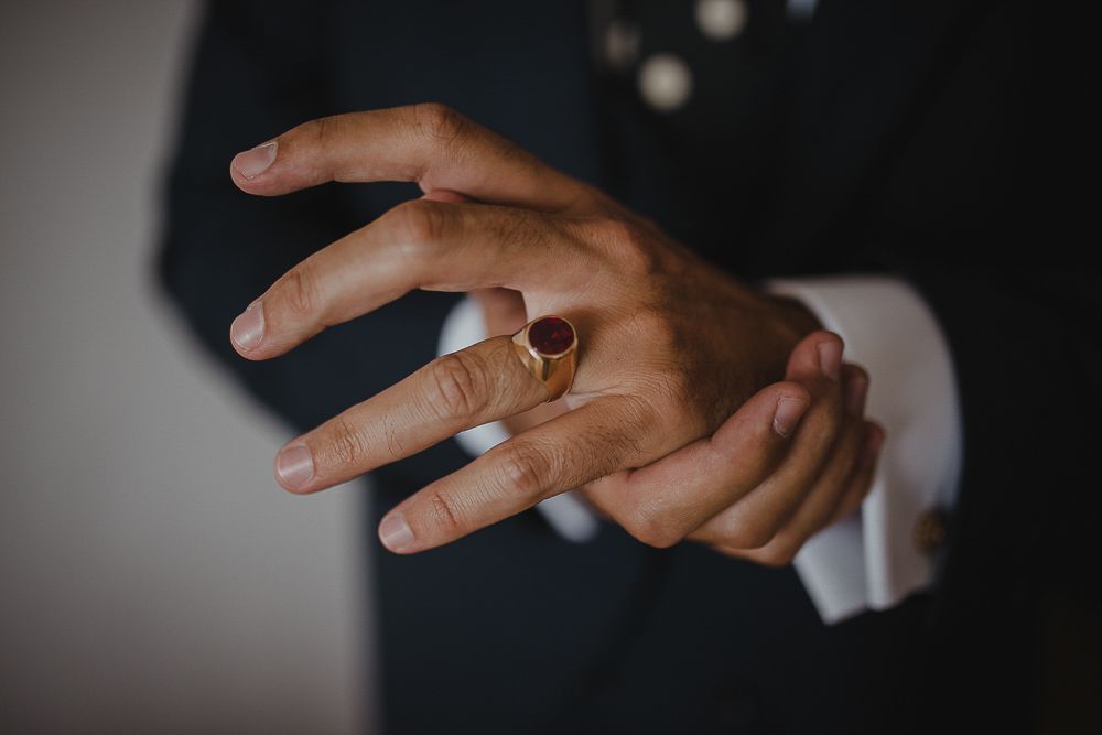 Close-up shot of hands displaying an elegant engagement ring against a dark background.