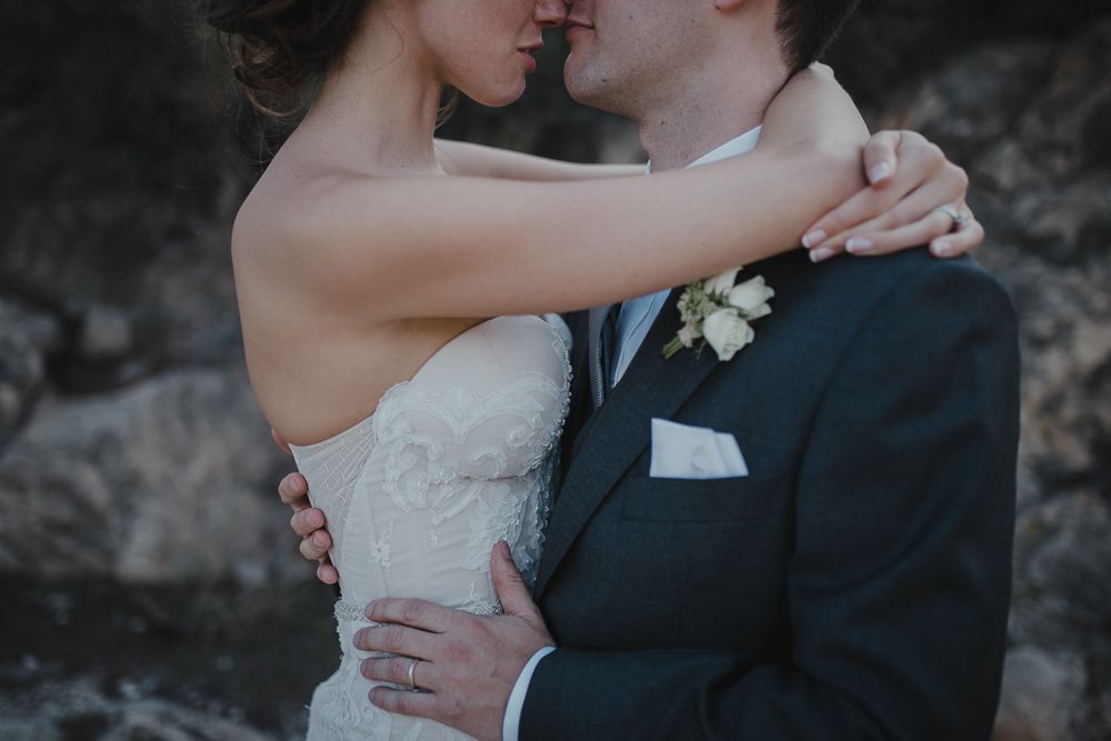 Intimate wedding portrait captured in soft, moody lighting against a dark background.