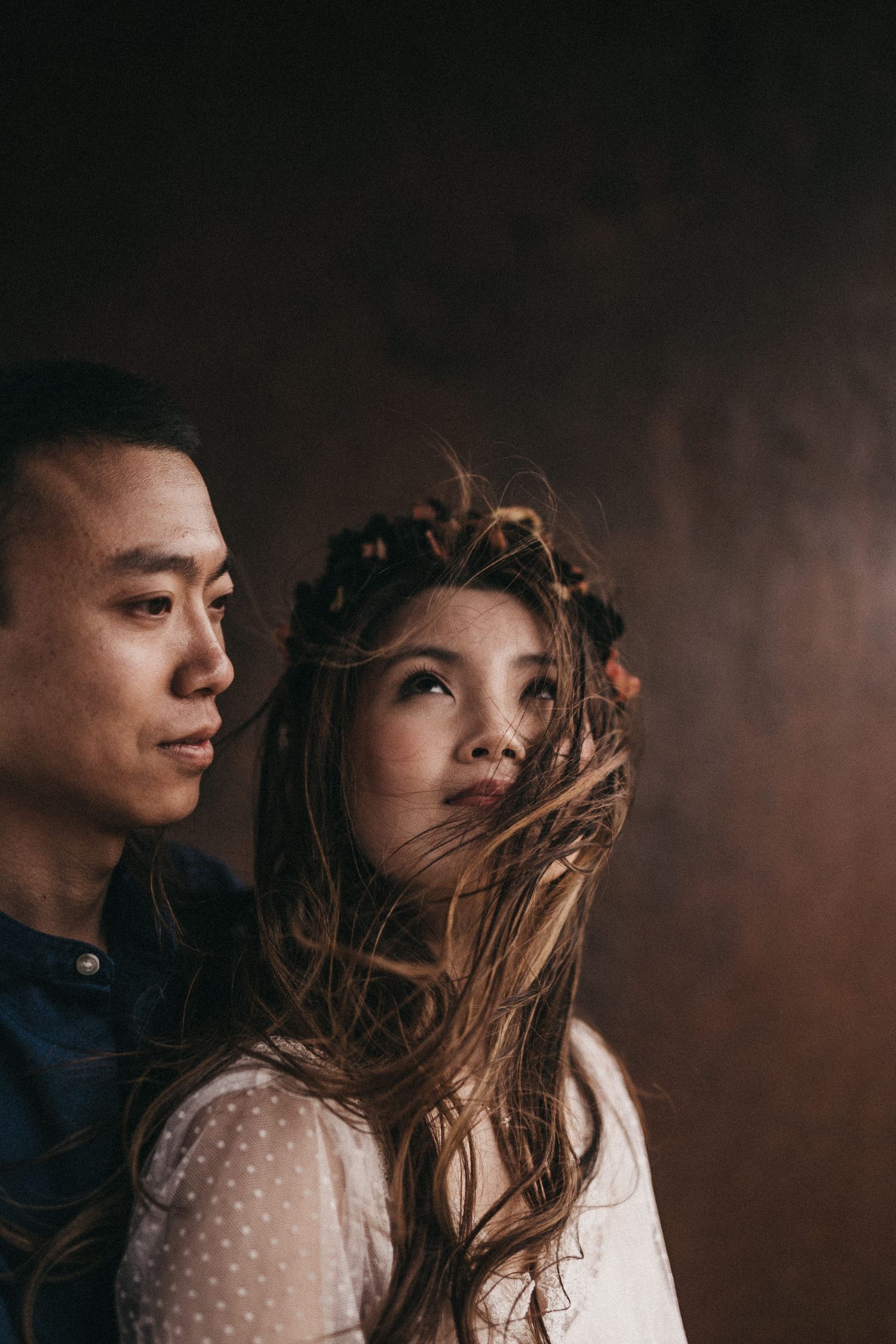 An artistic portrait with wind-swept hair against a moody brown backdrop.