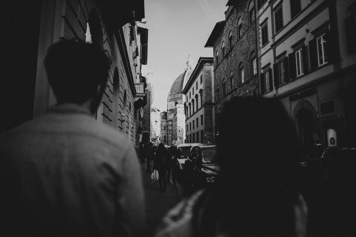 A black and white street scene in Florence showing historic architecture and pedestrians.