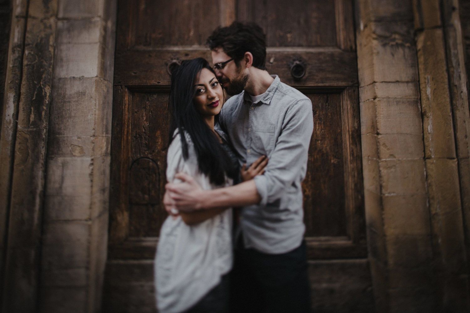 Intimate moment between couple against vintage wooden door in historic setting.