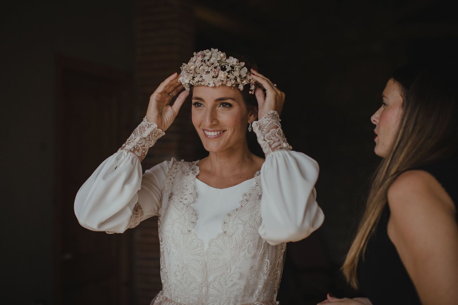 A delicate crystal headpiece is carefully positioned during bridal preparations.