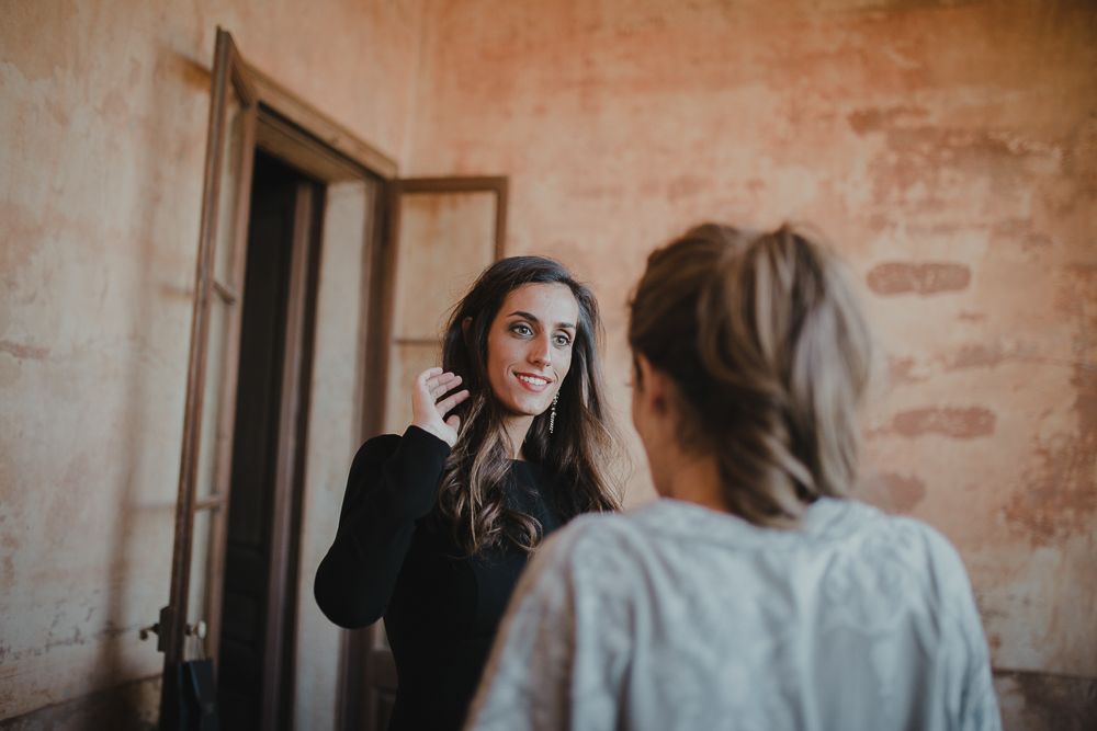 Two people in conversation against rustic pink wall with doorway.